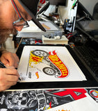 Jon Chase hand signing and numbering the Hot Wheels x DSTROYR limited edition fine art print at his studio, with the gasser burnout illustration visible on luster paper